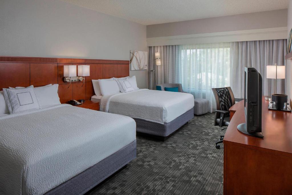 a hotel room with two beds and a desk with a television at Courtyard Orlando International Drive/Convention Center in Orlando