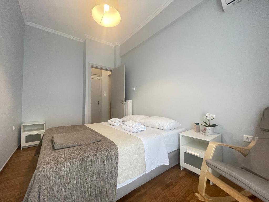 a white bedroom with a bed and a chair at Hermes - Acropolis Residence Apartment in Athens