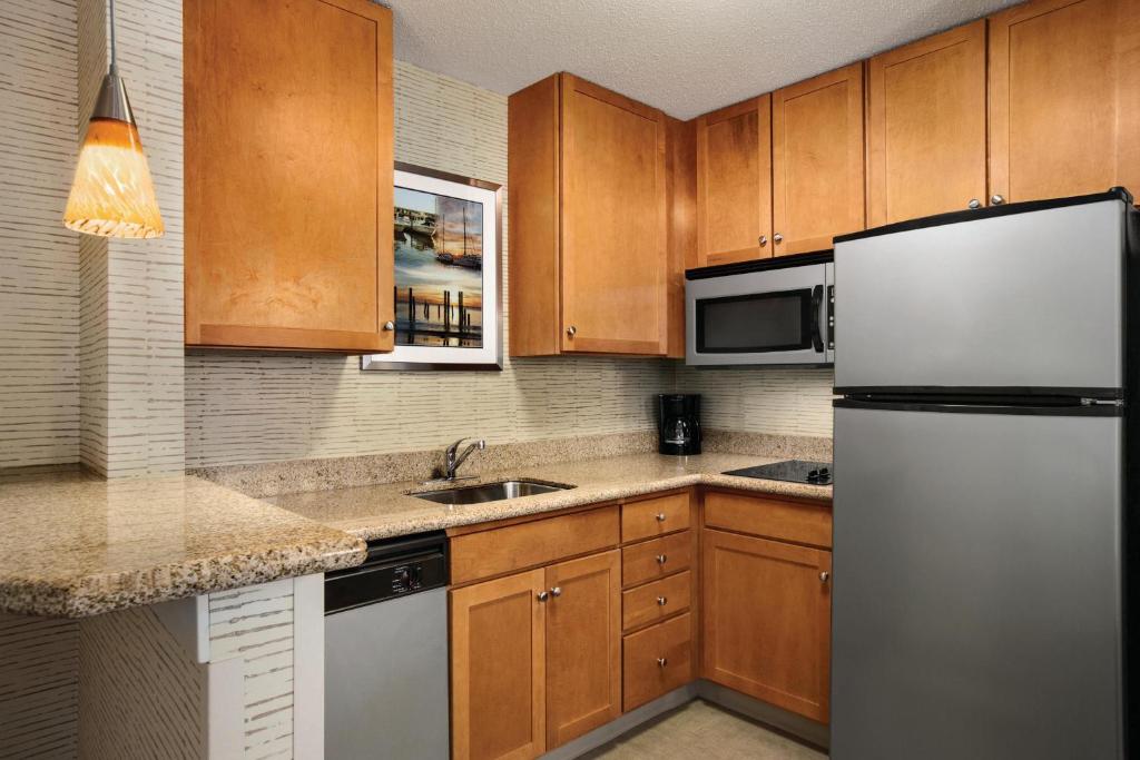 a kitchen with wooden cabinets and a refrigerator at Residence Inn by Marriott Newport Middletown in Middletown