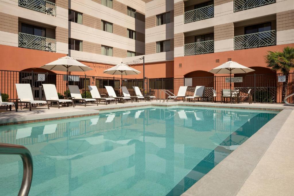 a swimming pool in front of a hotel with chairs and umbrellas at Courtyard by Marriott Scottsdale Old Town in Scottsdale