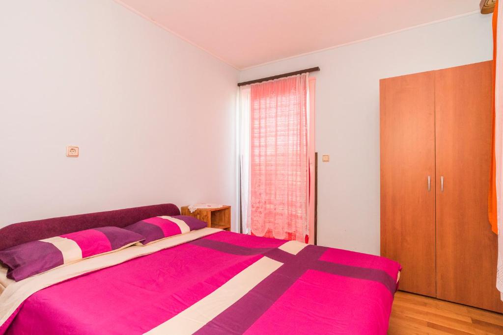 1 dormitorio con 1 cama grande con manta rosa en Studios Kaštel, en Buje