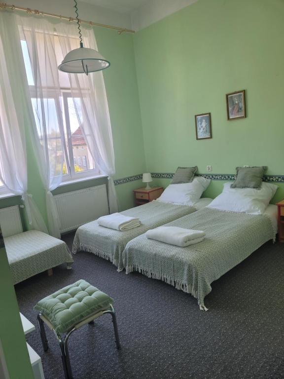 a bedroom with two beds and a chair and a window at Agroturystyka "Pałac w Janowie" in Janów