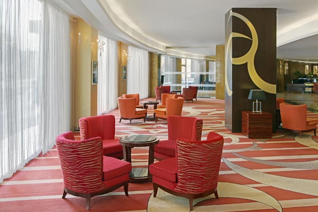 a waiting room with red chairs and tables at Four Points By Sheraton Riyadh Khaldia in Riyadh