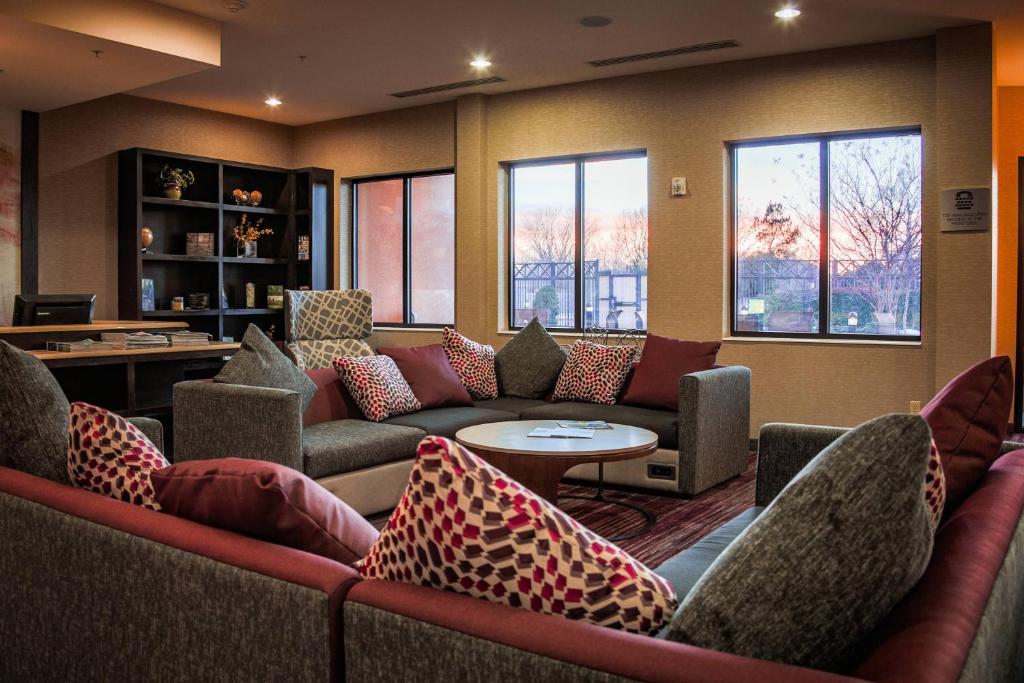 a living room with couches and a table and windows at Courtyard by Marriott Norman in Norman