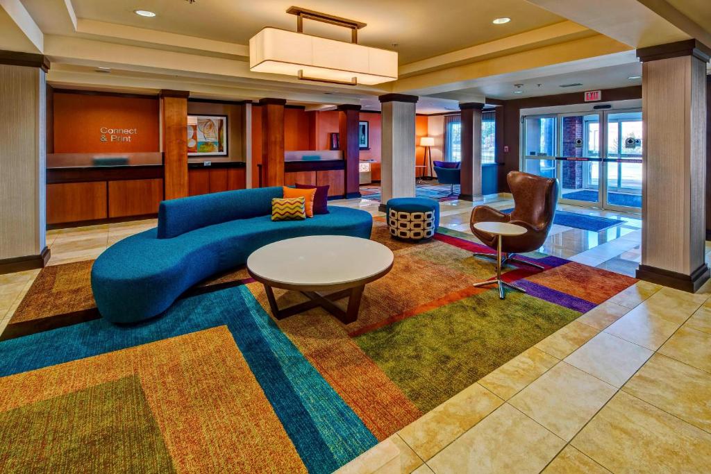 a lobby with a blue couch and a table and chairs at Fairfield Inn & Suites Memphis Olive Branch in Olive Branch