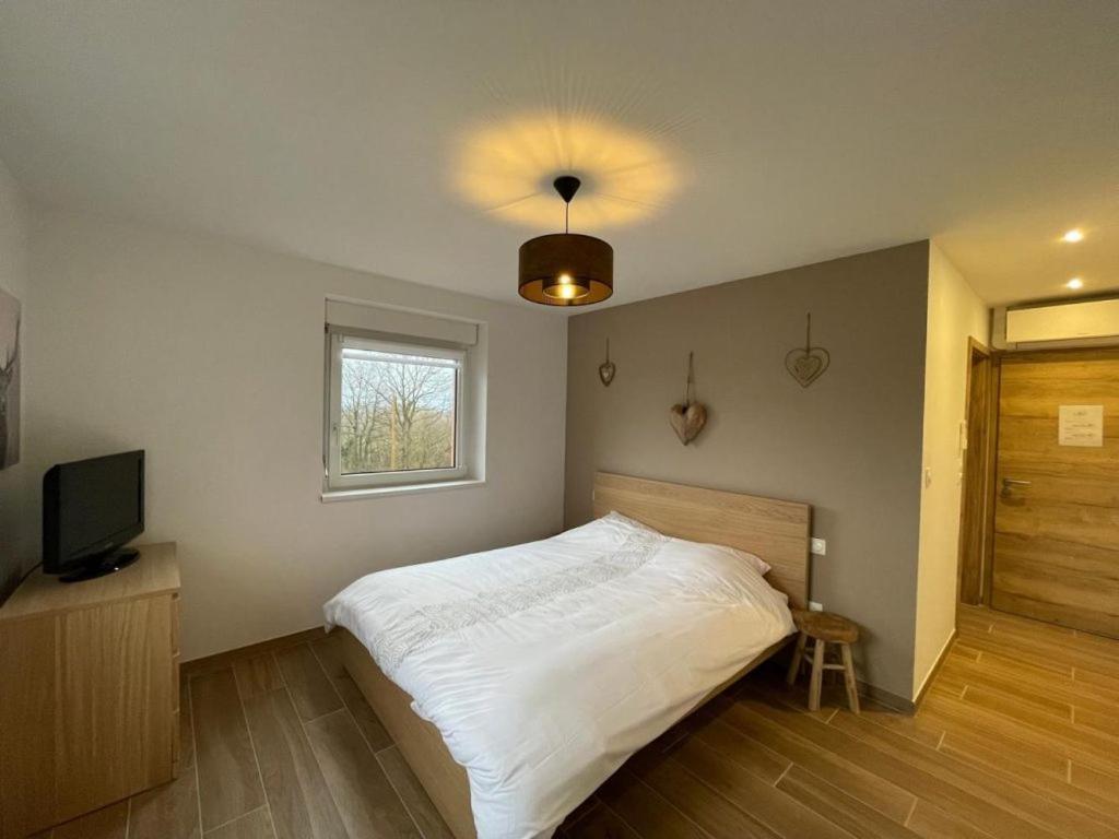 um quarto com uma cama branca e uma televisão em La Perle d'Alsace em Bernardswiller