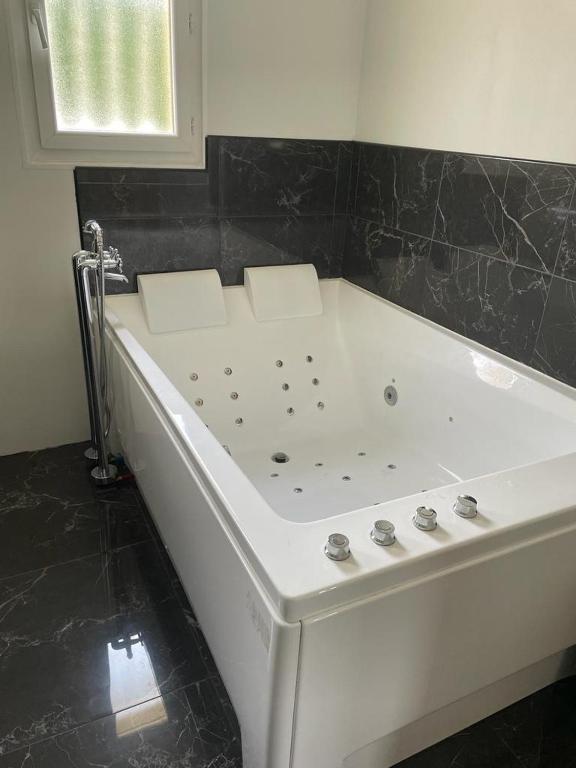 a white tub in a bathroom with a black tile wall at Villa Emma 10 &#47; 12 personnes in Grignan