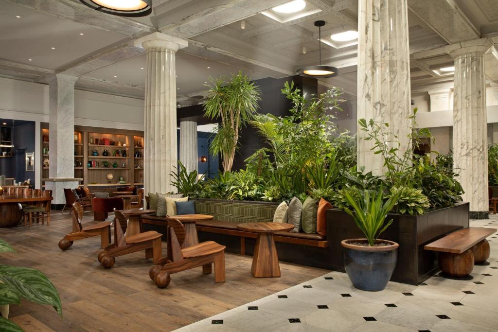a lobby with tables and potted plants at Emery Hotel, Autograph Collection in Minneapolis