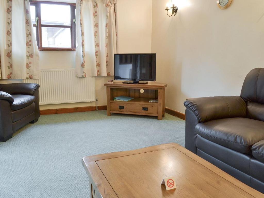 a living room with two couches and a flat screen tv at The Old Workshop - Ukc3740 in Bawdeswell