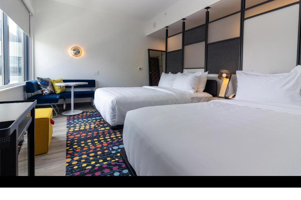 a hotel room with two beds and a desk at Aloft St. Louis Cortex in Saint Louis