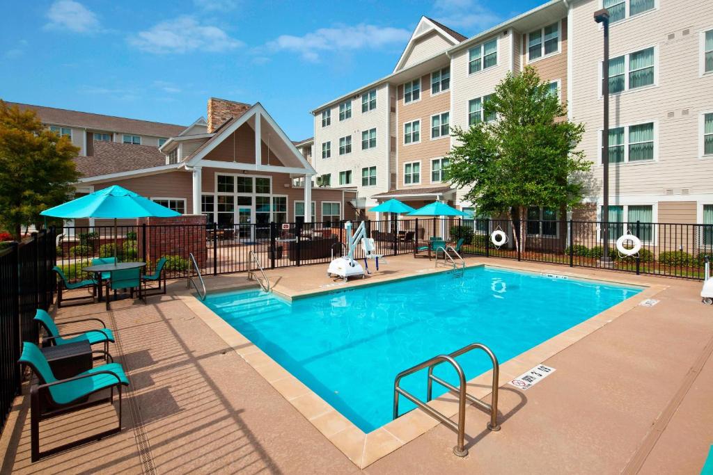 a swimming pool with chairs and tables and a building at Residence Inn by Marriott Covington Northshore in Covington