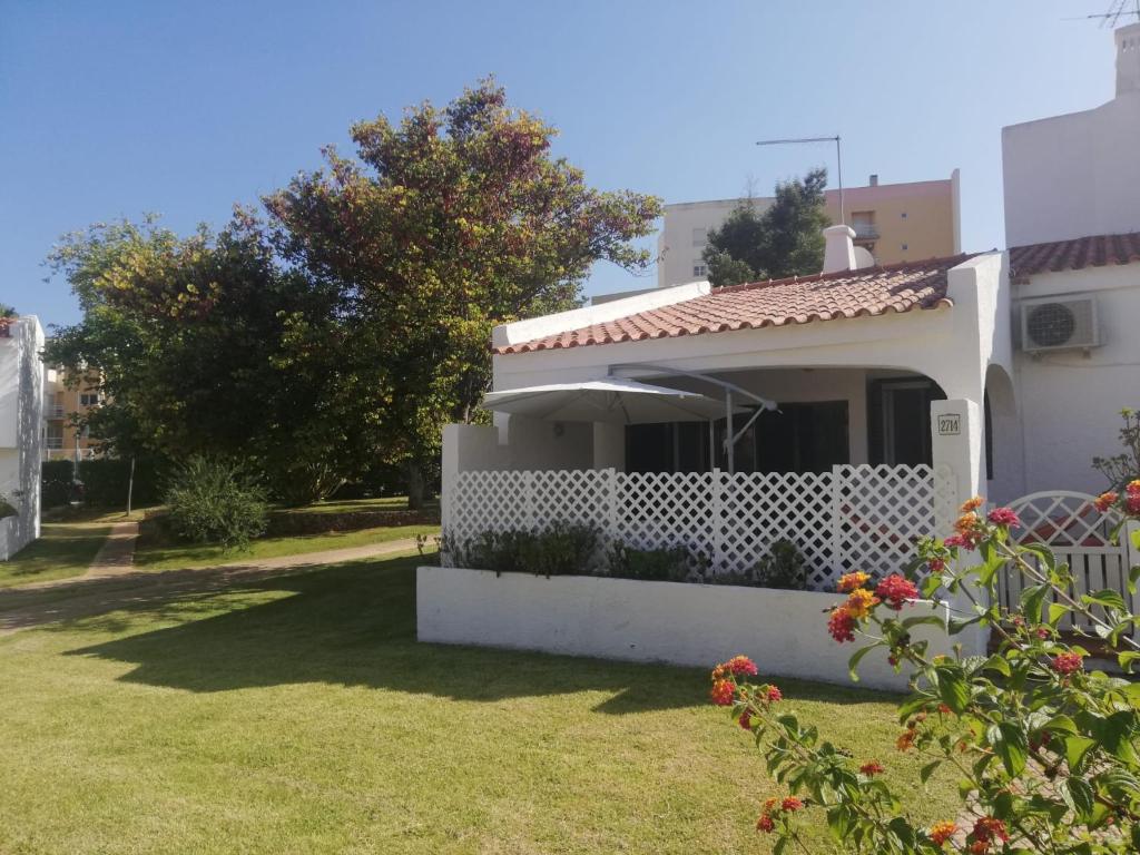 una pequeña casa blanca con un patio de césped en Vilamoura Alecrim, en Vilamoura