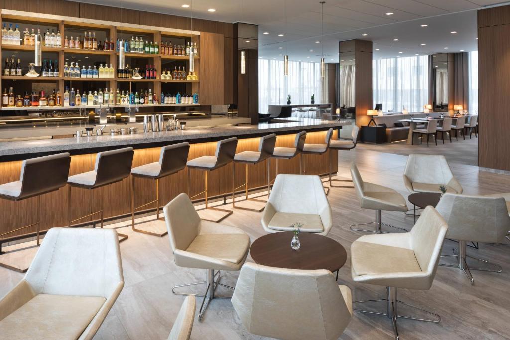 a bar in a hotel with white chairs and a counter at AC Hotel by Marriott Bloomington Mall of America in Bloomington