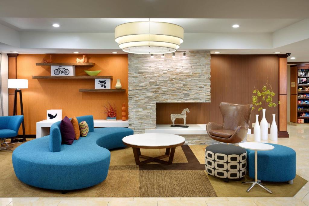 a living room with blue furniture and a fireplace at Fairfield Inn & Suites Salt Lake City Airport in Salt Lake City