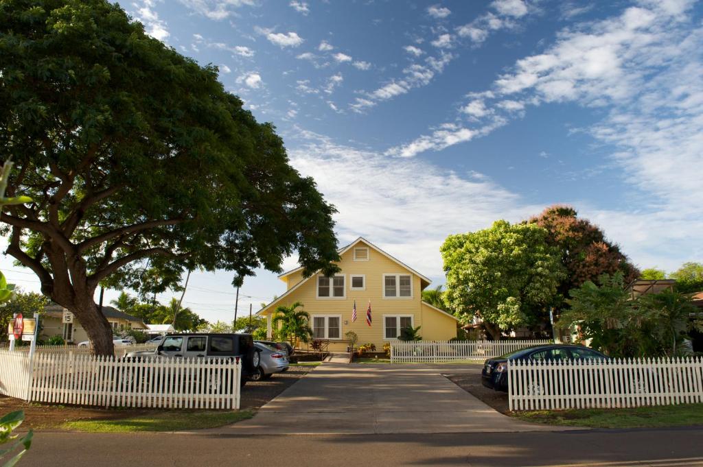 una casa amarilla con autos estacionados frente a ella en West Kauai Lodging, en Waimea