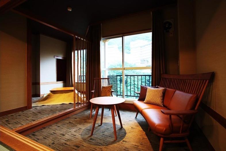 a room with a table and a chair and a window at Hotel Shirakawa Yunokura in Nikko