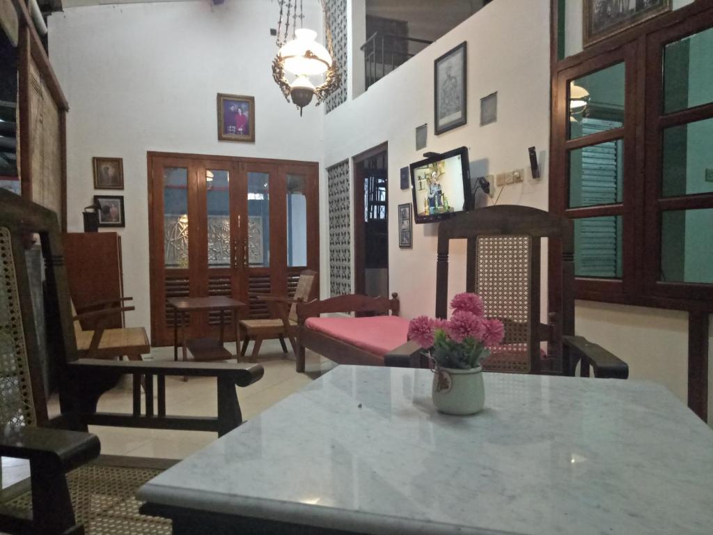 sala de estar con sillas y mesa con flores en Paviliun Omah Ndanu, en Yogyakarta
