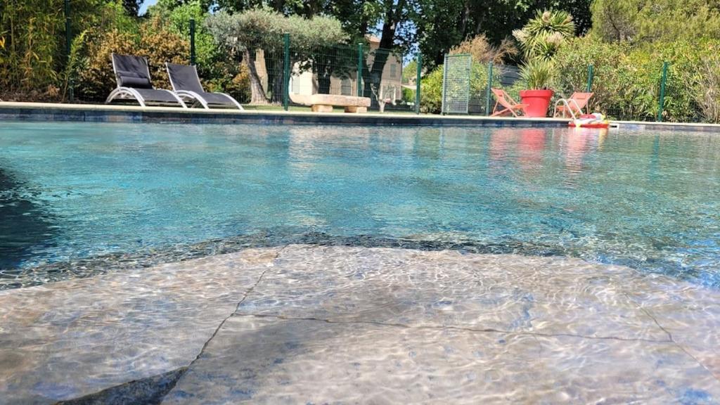 - une piscine avec 2 chaises dans l'eau dans l'établissement Bastide Sainte Marie, à Mallemort