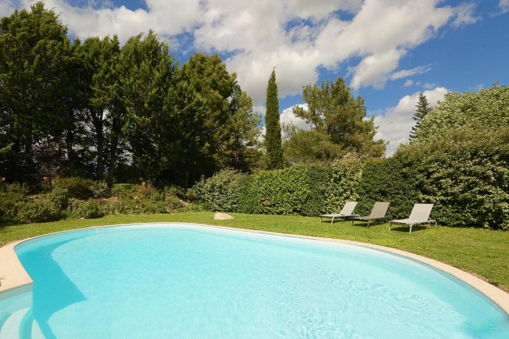 a swimming pool in a yard with two chairs at Bastide Magnolia - Les dépendances, Roussillon in Roussillon