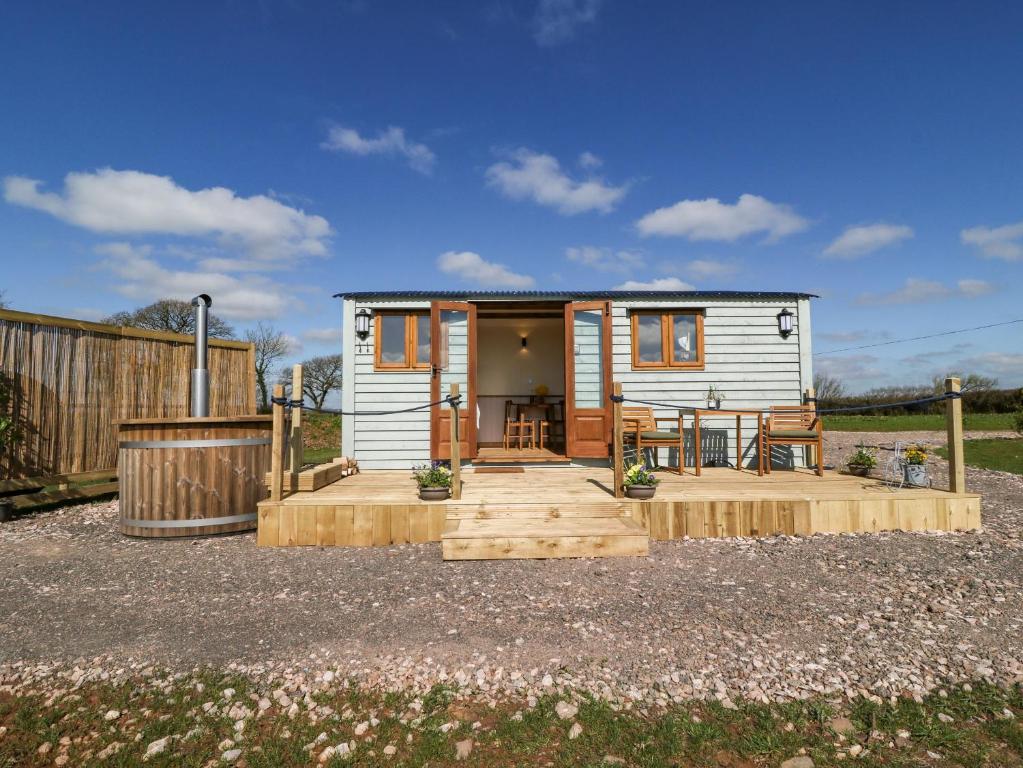 a small white tiny house with a patio at Buzzards in Crediton