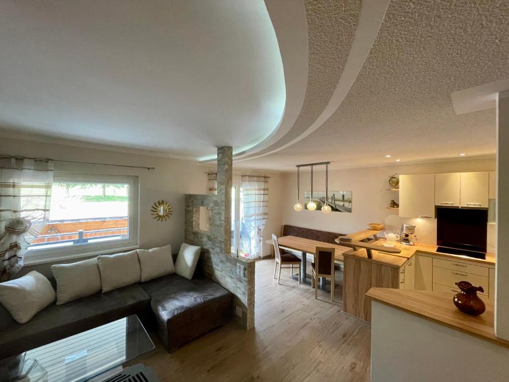 ein Wohnzimmer und eine Küche mit einem Sofa und einem Tisch in der Unterkunft Ferienwohnung Unterlerchner in Afritz