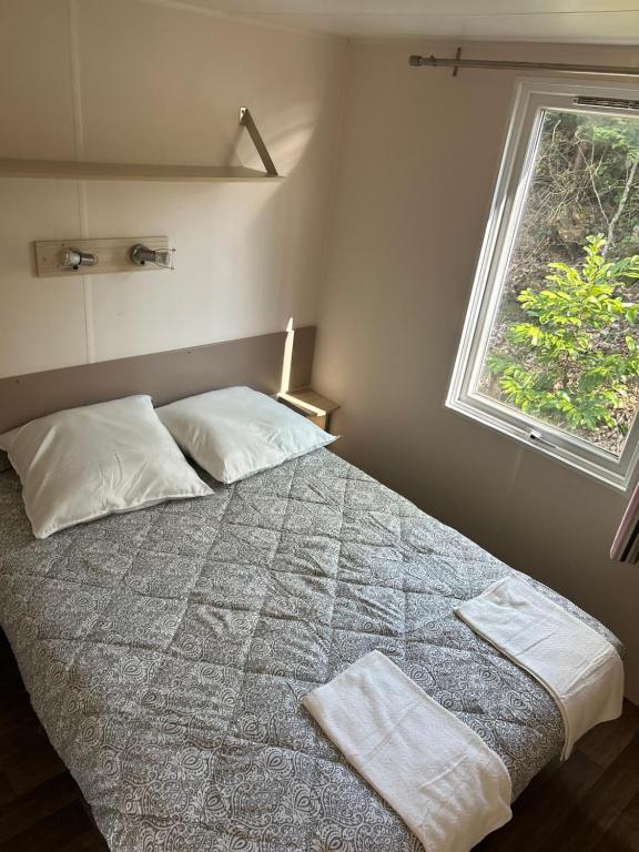 a bedroom with a bed with two pillows and a window at MobilHome 3 chambres 6 personnes Piscine Camping Saint Cheron in Saint-Chéron