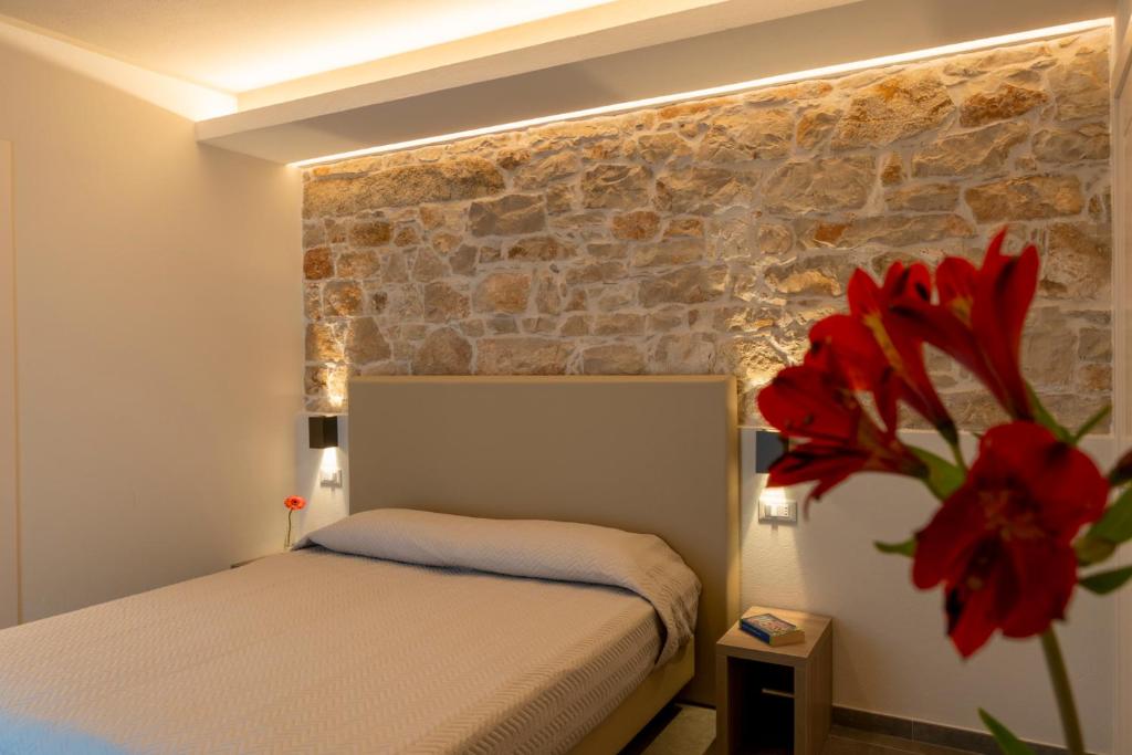 a bedroom with a bed and a brick wall at Goloritzè Room and Breakfast in Baunei