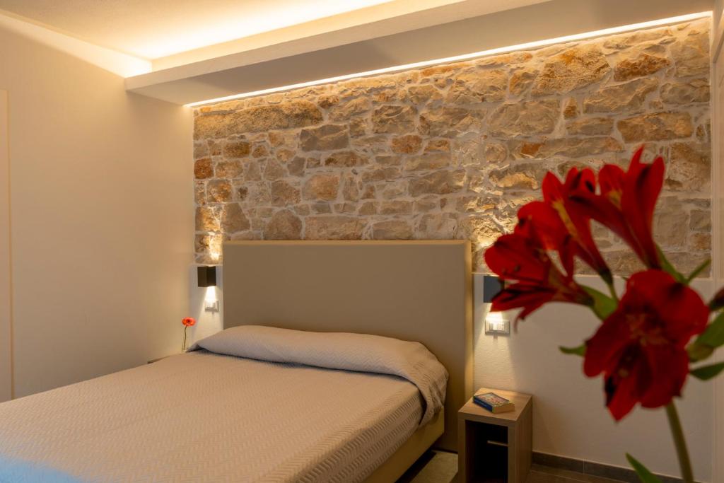 1 dormitorio con cama y pared de ladrillo en Goloritzè Room and Breakfast en Baunei