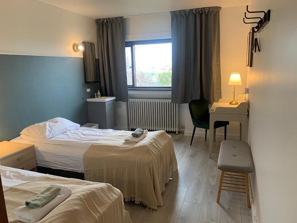 Habitación de hotel con 2 camas, escritorio y ventana en Travel Inn en Reikiavik