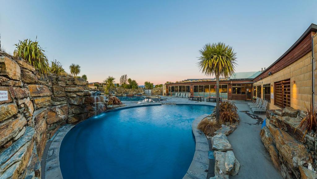 a swimming pool in a resort with a rock wall at Oakridge Resort Lake Wanaka in Wanaka