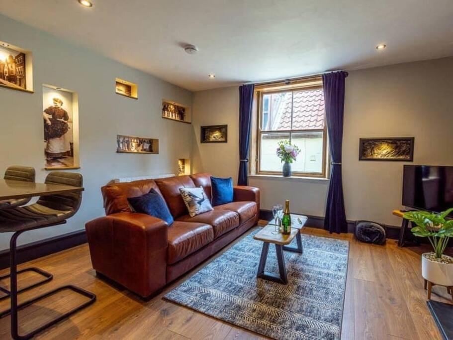 a living room with a brown leather couch and a table at One Over Eight in Whitby