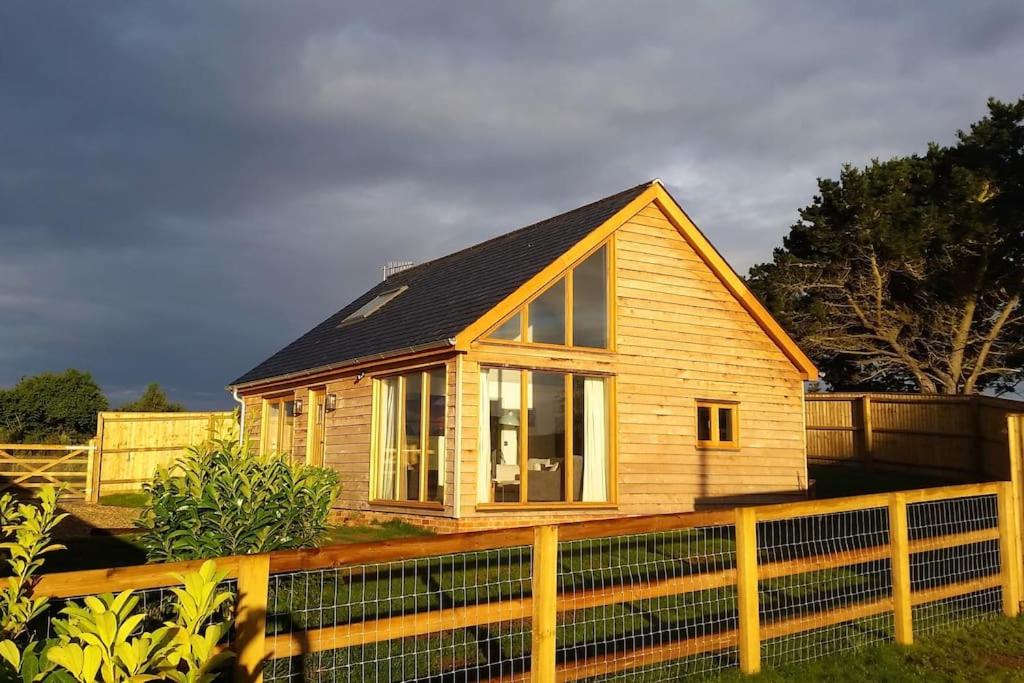 ein kleines Holzhaus hinter einem Zaun in der Unterkunft River Cottage - Stunning estuary views in Aldeburgh