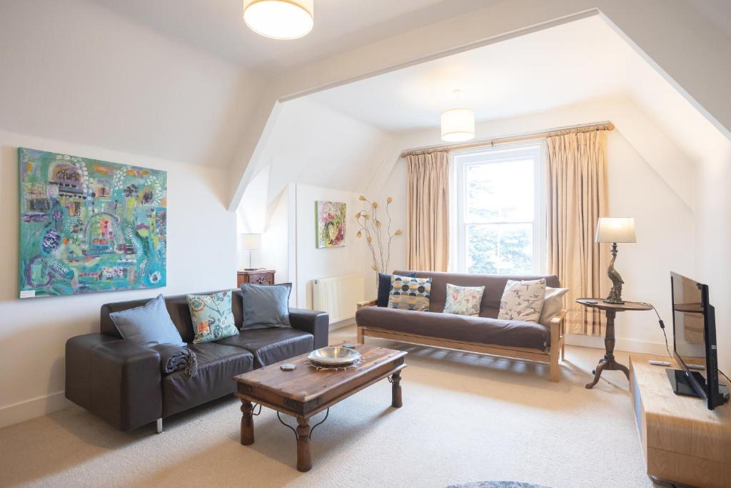 ein Wohnzimmer mit einem Sofa und einem Tisch in der Unterkunft Spacious 3BR Victorian Cheltenham loft flat in Cotswolds Sleeps 8 - FREE Parking in Cheltenham