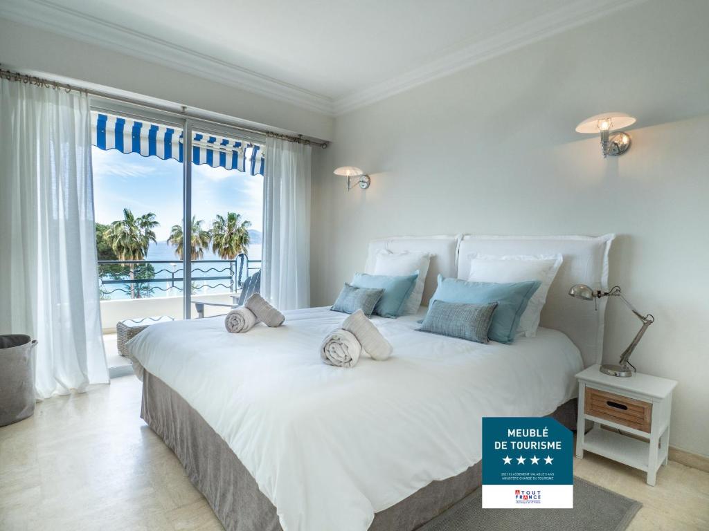 a bedroom with a large white bed with a large window at Cannes Croisette Superbe 3P front de mer in Cannes