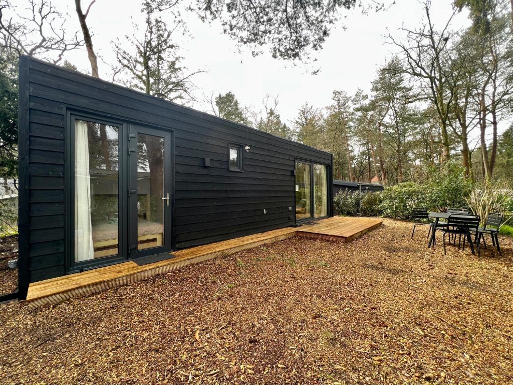 een zwart tiny house bovenop een yard bij Ultiem ontspannen in compleet ingericht tiny house in bosrijke omgeving in Nunspeet