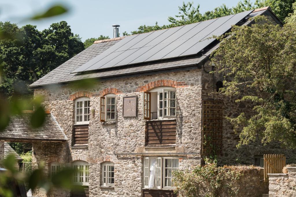 une ancienne maison en pierre avec des panneaux solaires sur le toit dans l'établissement Lower Marsh Farm in Cornwall, à Saltash
