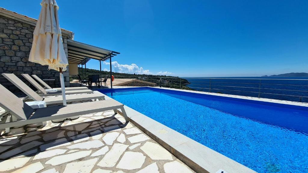 a villa with a swimming pool and a patio with an umbrella at Amousso Bay Villas in Marantochori