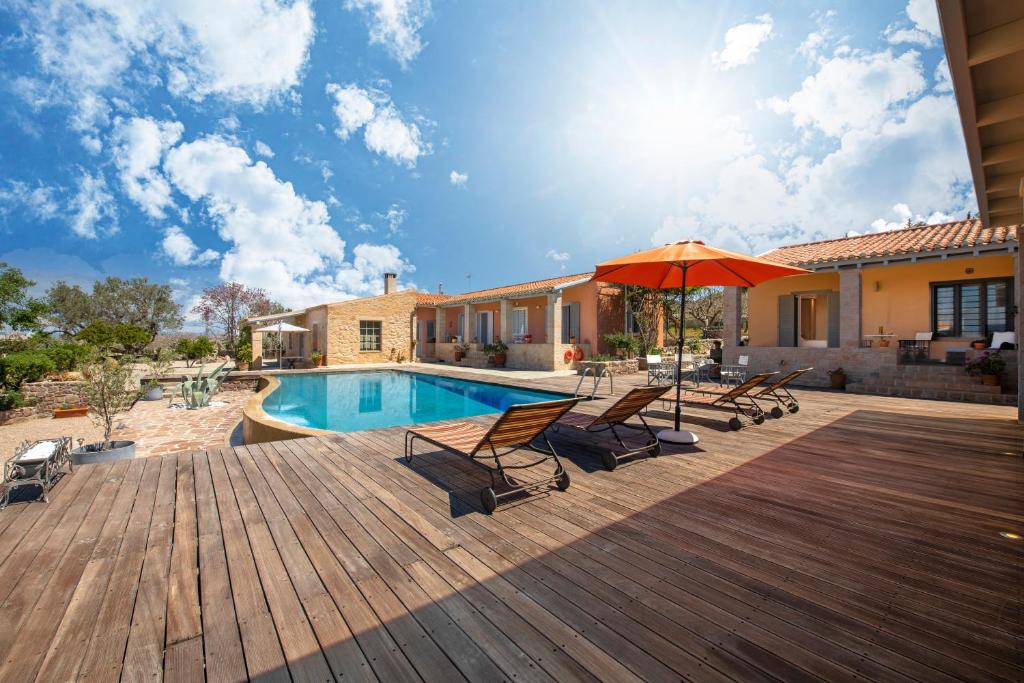 a deck with chairs and an umbrella next to a pool at Estate Prophet Elias in Aegina Town