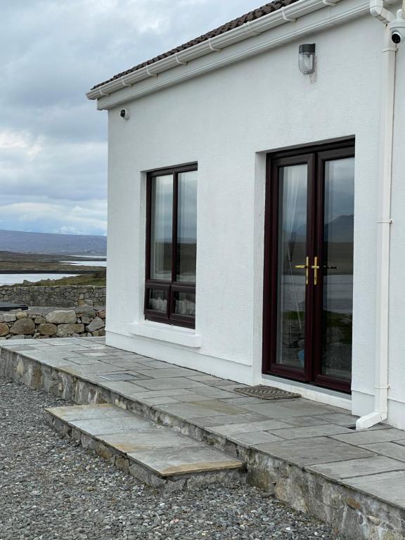 a white house with two windows and a walkway at Apartment at Island Cottage, Inishnee, Roundstone in Galway