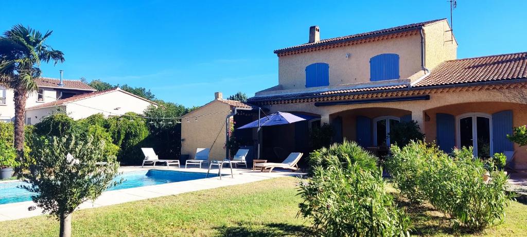 une villa avec une piscine en face d'une maison dans l'établissement Chambre et petit déjeuner, à Sérignan-du-Comtat