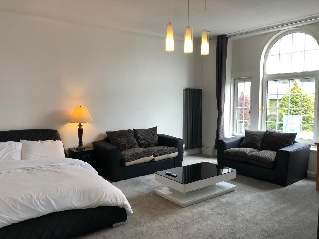 a bedroom with a bed and a couch and a table at Premier 2 bed Flat C in Broxburn