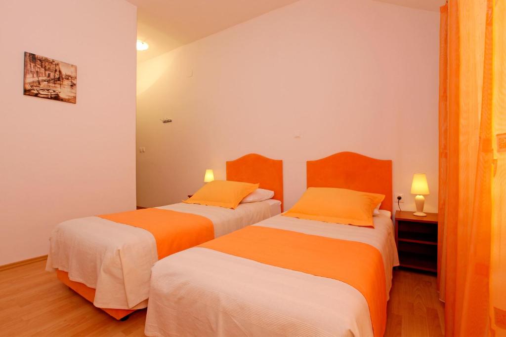 2 Betten in einem Zimmer in Orange und Weiß in der Unterkunft Guest House Kod Peskarije in Vela Luka