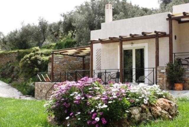 una pequeña casa con flores delante en Naiades Villas, en Caristo
