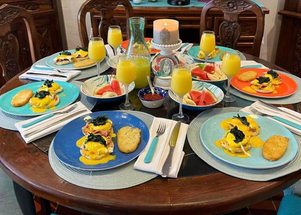 une table en bois avec des assiettes de nourriture et de jus d'orange dans l'établissement The Mermaid and The Pearl Boutique B&B, à Isla Mujeres
