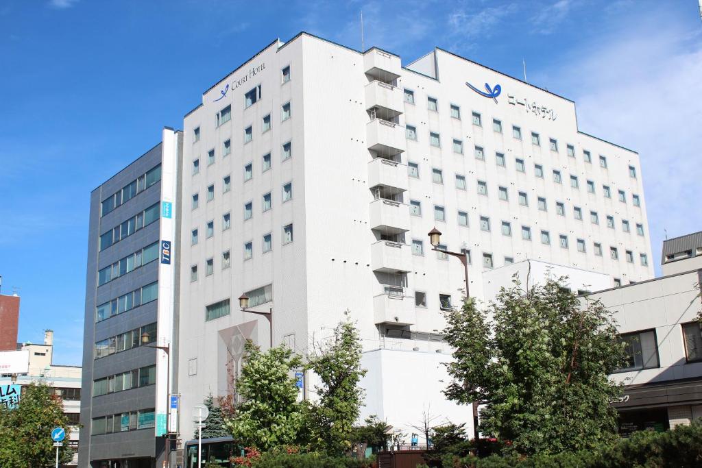 um edifício branco com um cartaz em Court Hotel Asahikawa em Asahikawa