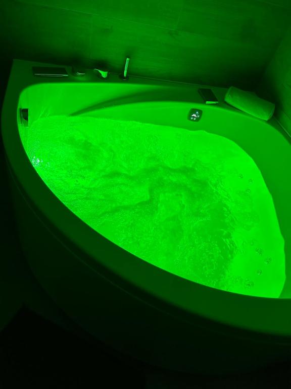 El baño incluye una bañera verde llena de agua verde. en Luxury Apartment with Jacuzzi en Santiago de Compostela