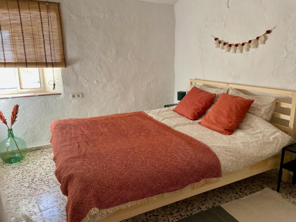 una camera da letto con un letto con cuscini arancioni di Casa Torreta village house with great views a Sedella