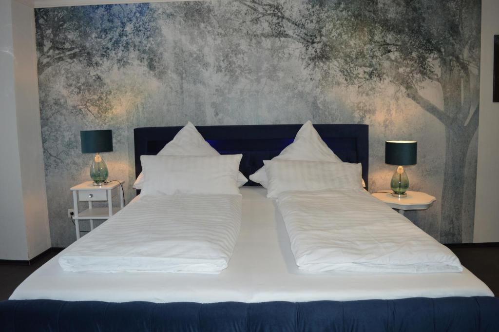 een groot bed met witte lakens en kussens bij Dolomitenblick in Gerolstein