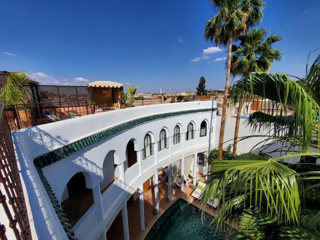 a bridge over a pool in a resort with palm trees at Riad Chergui in Marrakech