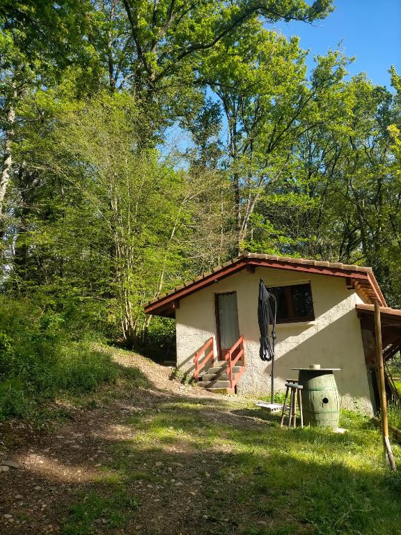une cabane dans les bois avec une table et un parasol dans l'établissement L'Aire du paon, à Aire-sur-lʼAdour